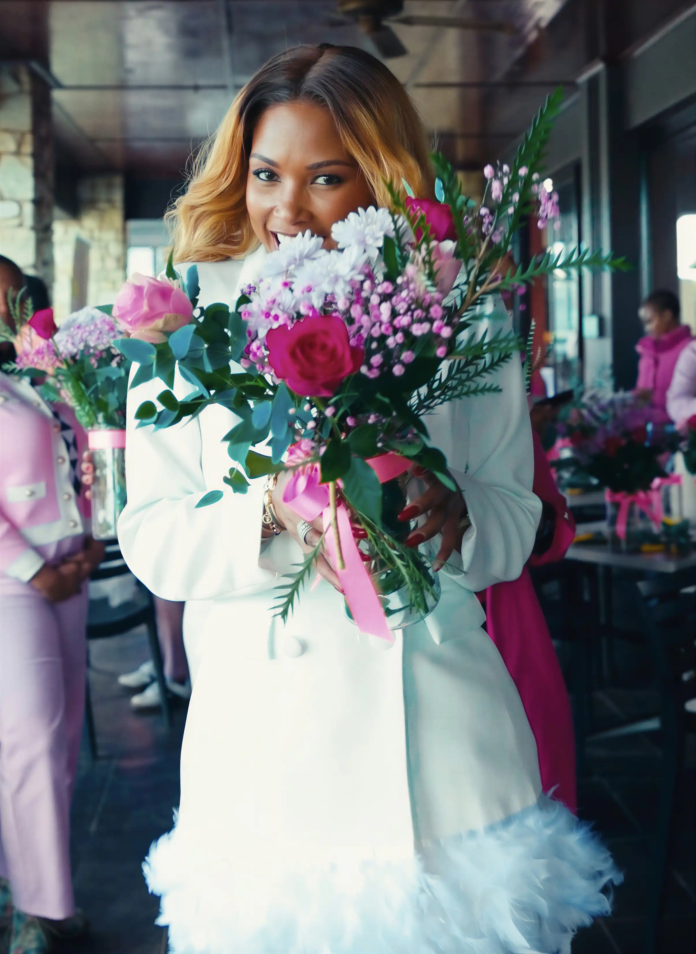Woman proudly holding a stunning floral bouquet she arranged at Sip n Snip