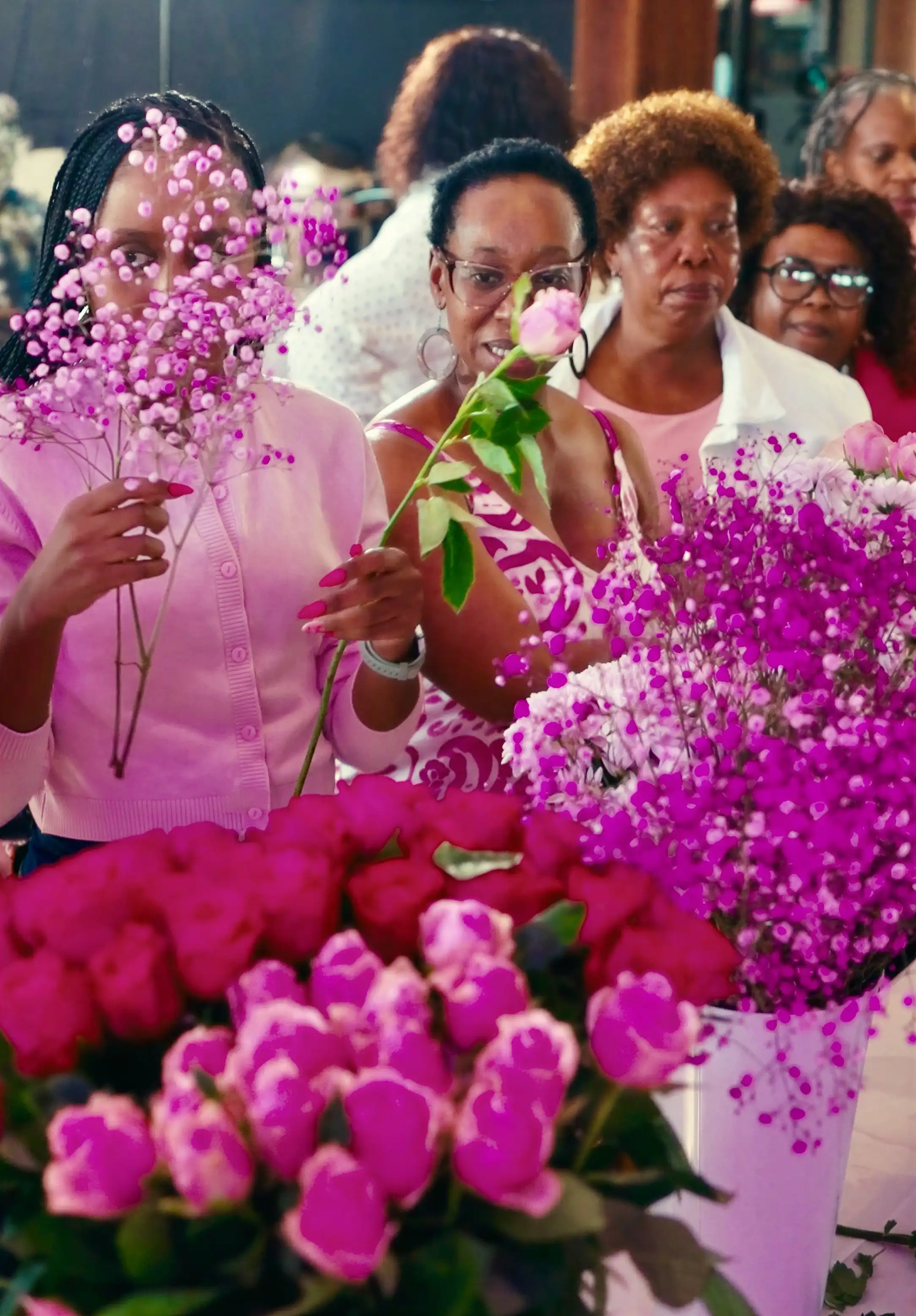 Women joyfully selecting vibrant pink flowers to arrange at Sip n Snip