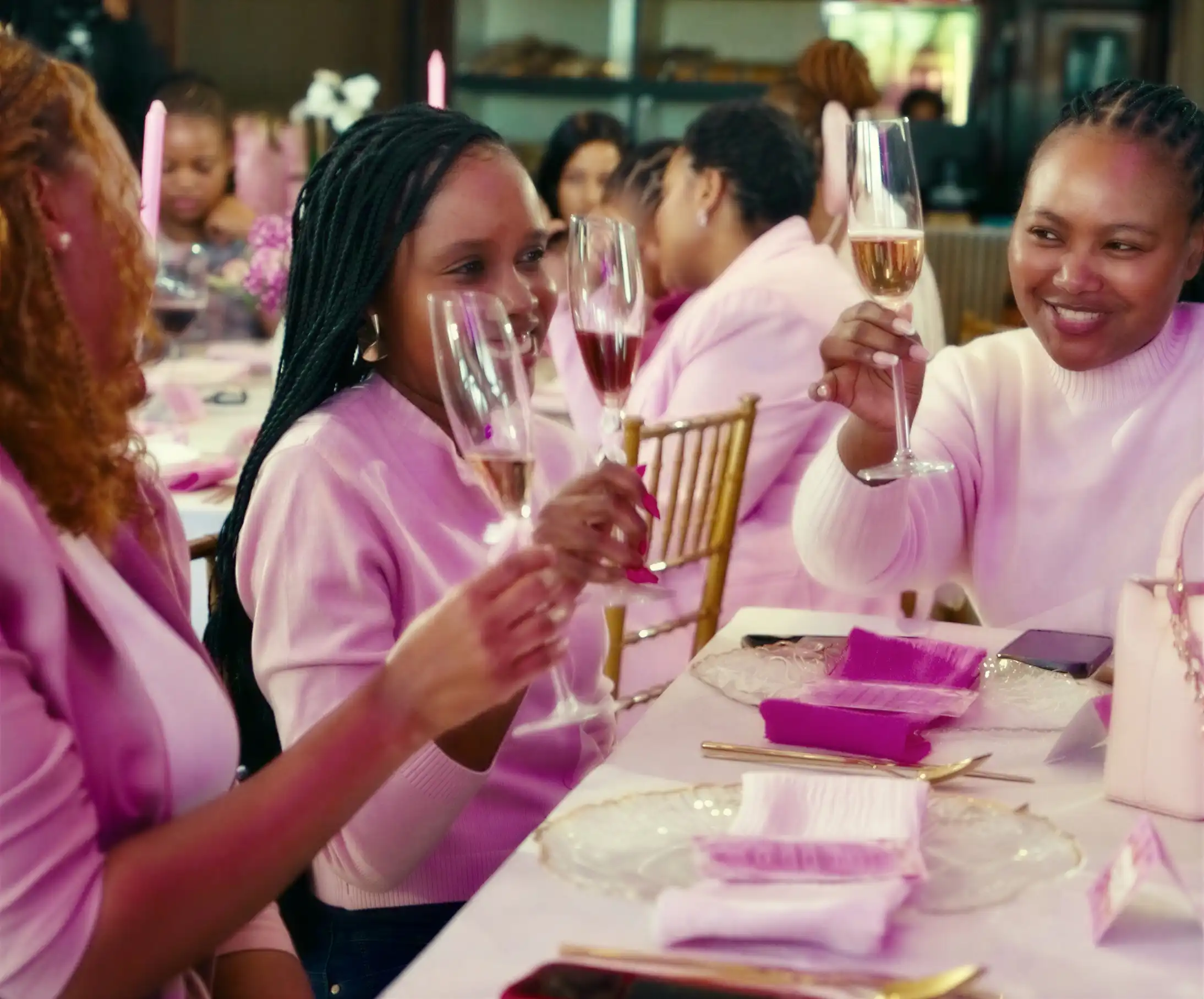 Women raising champagne glasses in a joyful toast at Sip n Snip